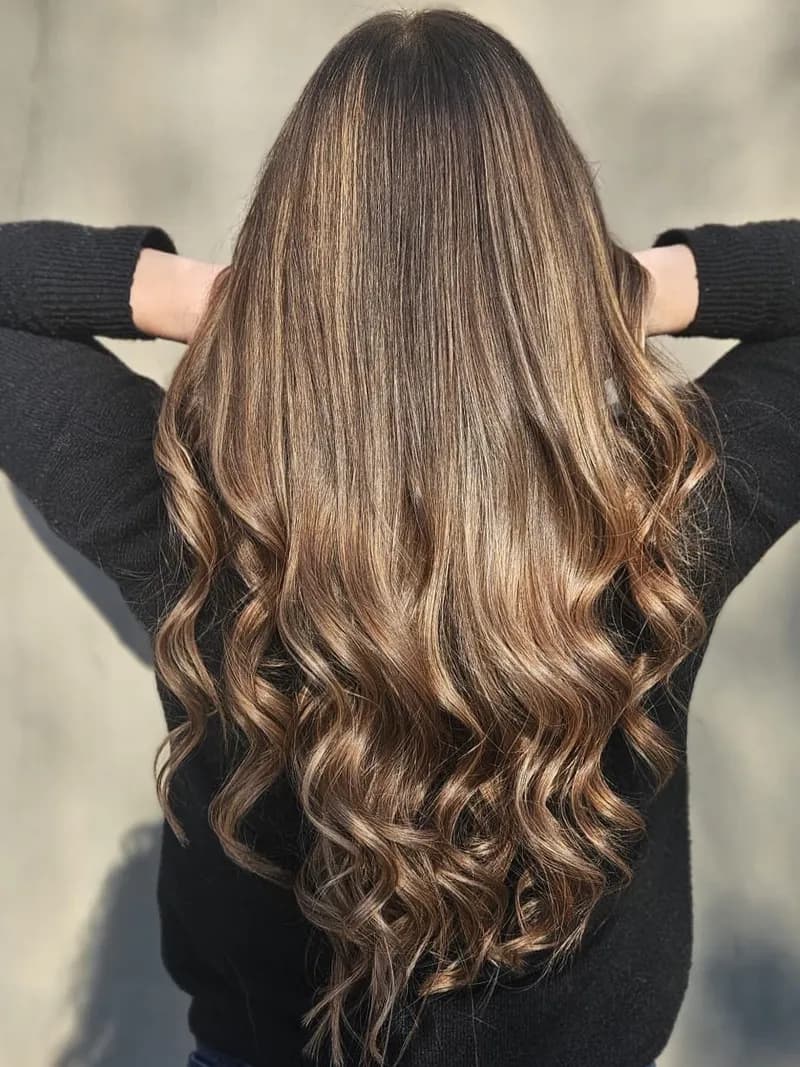 Cheveux longs bouclés, éclaircissement doux sur base naturelle, vus de dos